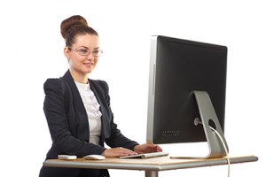 Beautiful girl sitting at table and stares at computer screen
