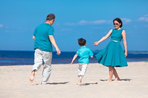 Young family of three having fun tropical beach