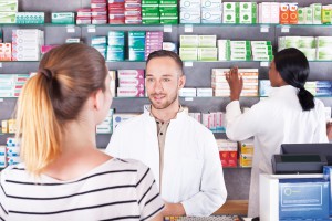 Pharmacist attending customer, showing product