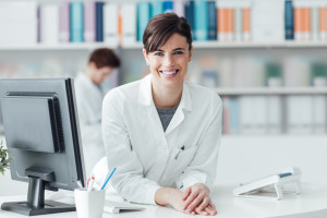 Smiling female doctor at the clinic reception desk, healthcare and professionalism concept