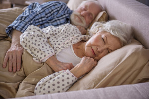 Tranquil married couple lying in bed and sleeping. Old husband i