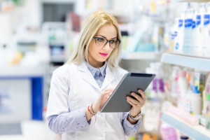 Pharmacy details - blonde doctor in white uniform using tablet a