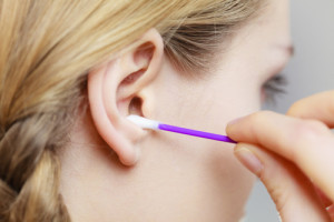 Woman cleaning ear with cotton swabs closeup