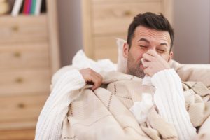 Man blowing his nose in bed